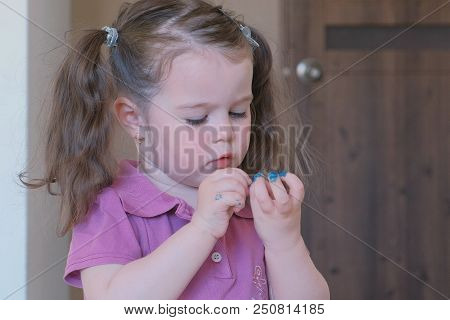 Little Cute Girl Paints Her Nails With Blue Varnish
