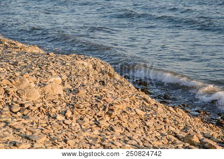 Pebbles On The Beach Pebbles On The Sea Shore And Waves Of Water Illuminated By The Rays Of The Sun