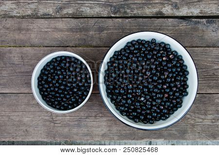 Beautiful Natural Black Berries In Asmall And Large Bowls On Wooden Background Top View.