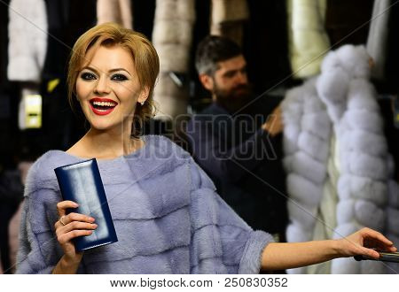 Lady Tries Expensive Mink Overcoats On. Seller With Beard And Woman Choose Furry Coat. Man And Girl 