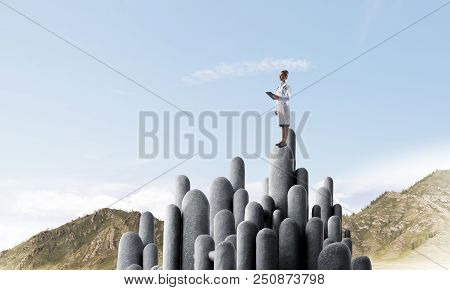Young Female Doctor With Folder In Hands Satnding On Stone Column