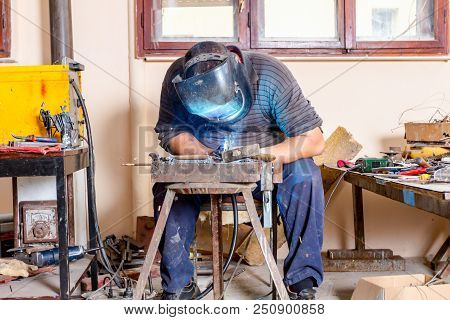 Sculptor Is Using Arc Welding To Assembly Metal Sculpture Barehanded With Protective Mask.