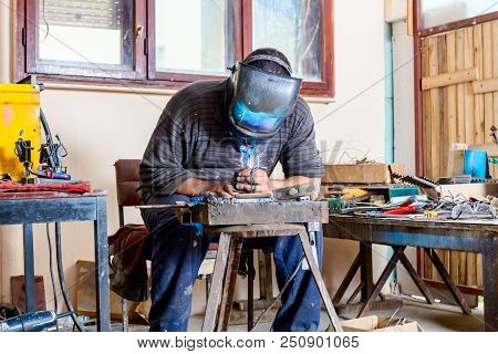 Sculptor Is Using Arc Welding To Assembly Metal Sculpture Barehanded With Protective Mask.