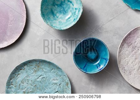 Multi-colored glay vintage handmade dishes. Flat lay. Set of porcelain blue bowls on a gray concrete table.