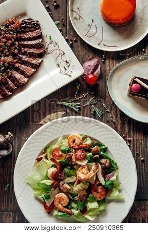 Menu Composition Of Dishes Decorated With Included Seafood Salad, Meat And Cake