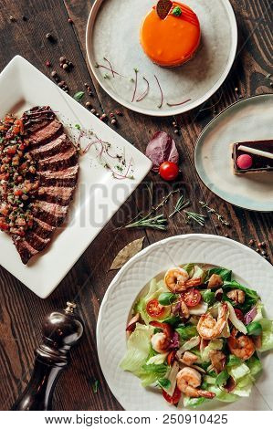 Menu Composition Of Dishes Decorated With Included Seafood Salad, Meat And Cake
