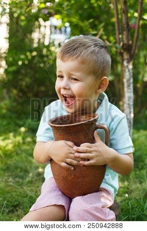 Cute Little Boy Holding A Old Clay Pot. Milk Jug.