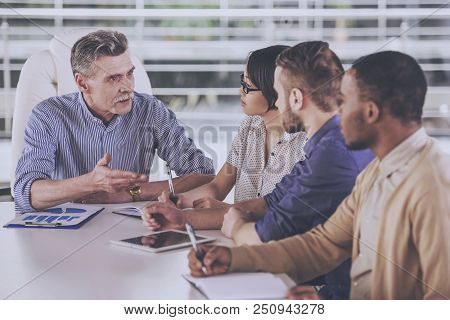 Multinational Group Of People Discuss In Office. Business Concept. Four People At Work. Managing Iss