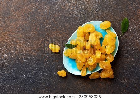Dried Yellow Kumquat With Green Leaves On Brown Background. Top View.
