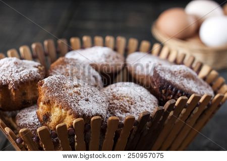 On A Wooden Table There Are Cupcakes In A Wooden Breadbasket