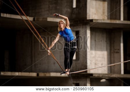 Female Equilibrist Standing Tilted Her Hands In The Right Direction On The Slackline On The Backgrou