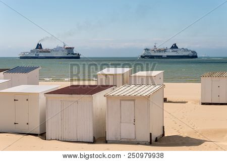 Calais, France - 19 June 2018: Beach Cabins And Dfds / P&o Cross Channel Ferries.