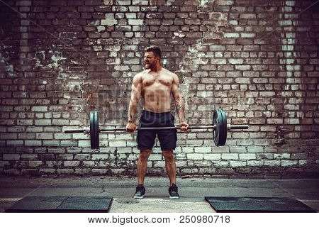 Muscular Fitness Man Doing Deadlift A Barbell Over His Head In Outdoor, Street Gym. Functional Train