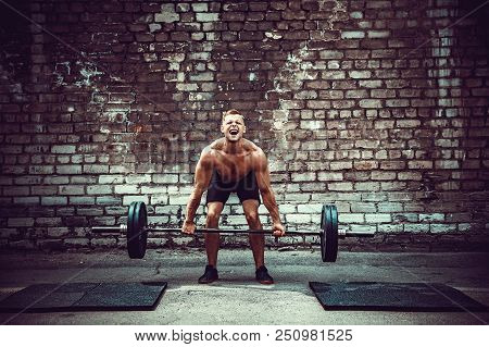 Muscular Fitness Man Doing Deadlift A Barbell Over His Head In Outdoor, Street Gym. Functional Train