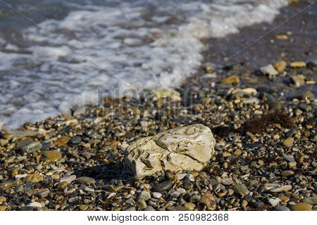Pebbles On The Beach Pebbles On The Sea Shore And Waves Of Water Illuminated By The Rays Of The Sun