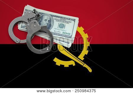 Angola Flag  With Handcuffs And A Bundle Of Dollars. The Concept Of Breaking The Law And Thieves Cri