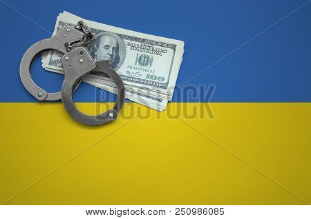 Ukraine Flag  With Handcuffs And A Bundle Of Dollars. The Concept Of Breaking The Law And Thieves Cr
