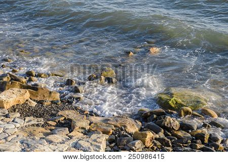 Pebbles On The Beach Pebbles On The Sea Shore And Waves Of Water Illuminated By The Rays Of The Sun