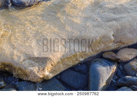 Pebbles On The Beach Pebbles On The Sea Shore And Waves Of Water Illuminated By The Rays Of The Sun