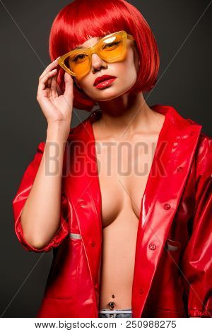 Close-up Portrait Of Seductive Young Woman In Red Latex Jacket On Bare Skin And Vintage Yellow Sungl