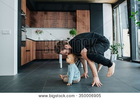 Father Standing On His Fingers While Kissing His Babys Head.