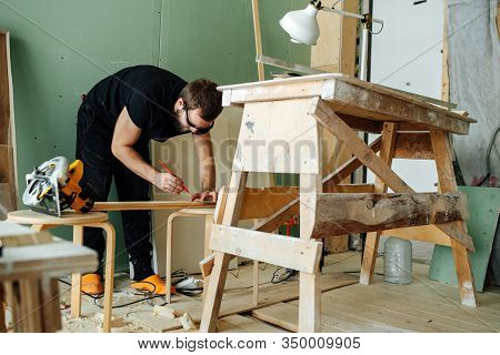 Bearded Man Making Marks On A Plank. Hes Working On Renovating His Apartment.