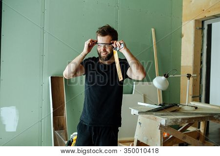 Happy Bearded Man Standing With Corner Ruler In Rennovating Apartment.