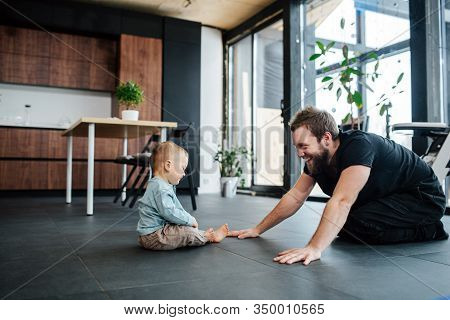 Father Exercising, Streching Next To His Infant Baby, Looking At Him