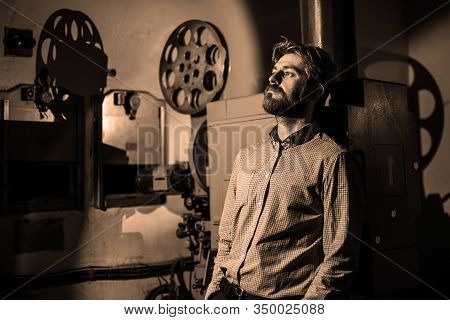 Beautiful Hipster Man Standing Near A Film Projector In The Room Projectionist