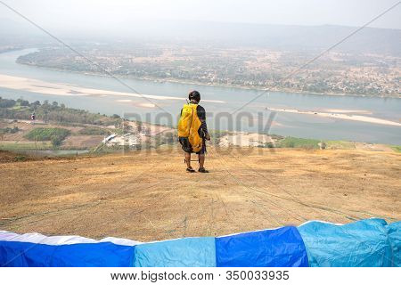 Paraglider On The Ground. Paragliders With Full Flight Equipment Look On Soaring Another Paragliders