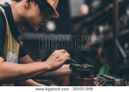 Closeup Side View Of Early 40's Male Employee At A Factory Plant Operating A Production Line Machine