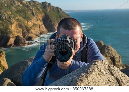 Cabo Da Roca, Portugal - February, 2019: A Young Photographer Takes A Photo Near A Cliff Against The