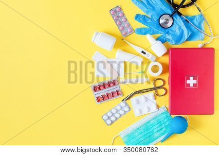 First Aid Kit Red Box With Medical Equipment And Medications For Emergency Top View On Pastel Yellow