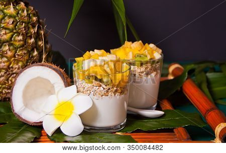 Exotic Tropical Fruit Salad With Muesli And Yogurt In A Glasses On The Palm Leaf.
