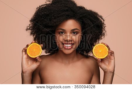 Beautiful African Female Model With Curly Hair Smiling And Showing Halves Of Fresh Orange Full Of Vi