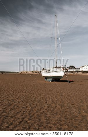 Sail Boat Moored With An Anchor On The Beach At Low Tide At Instow Beach North Devon