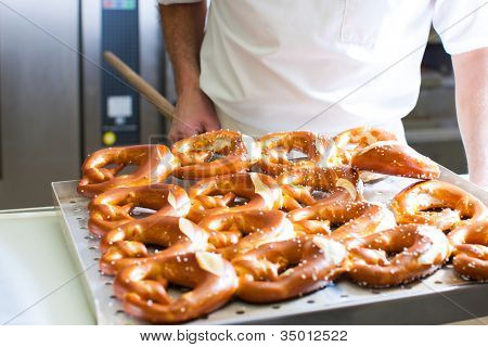 Mężczyzna piekarz wypiek świeży chleb w bakehouse, jest produkcji brezn