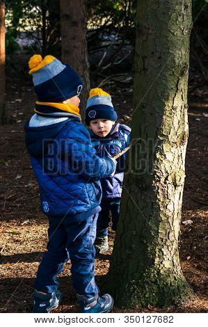 Poznan, Poland - February 9, 2020: Two Boys Playing With A Stick Around A Tree Stem In The Cytadela 