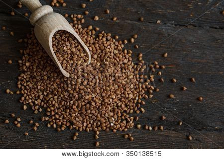 Scoop And Buckwheat Macro View On Rustic Background. Close Up Raw Buckwheat Background.