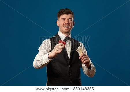 Noob In Poker, In Black Vest And White Shirt. Holding Two Red Chips And Aces. Posing Against Blue Ba