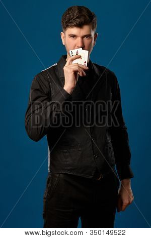 Noob In Poker, In Black Vest, Trousers And Shirt. Holding Two Playing Cards While Posing Against Blu