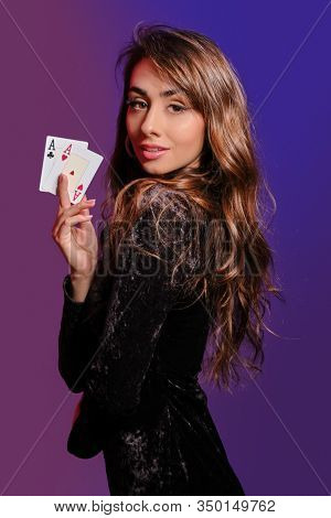 Brunette Girl In Black Velvet Dress Showing Two Playing Cards, Posing Sideways On Coloful Background