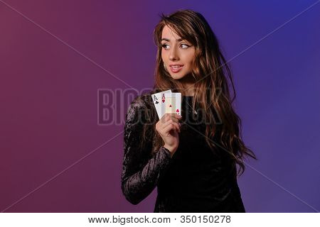 Brunette Woman In Black Velvet Dress Showing Two Playing Cards, Posing Against Coloful Background. G