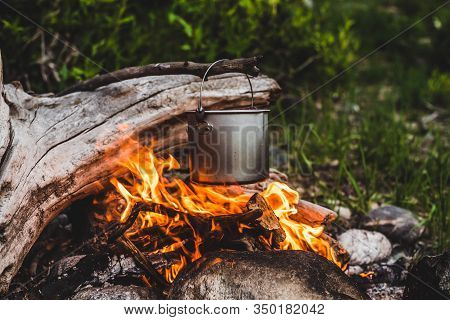 Kettle Hanging Over Fire. Cooking Food At Fire In Wild. Beautiful Big Log Burns In Bonfire Close-up.