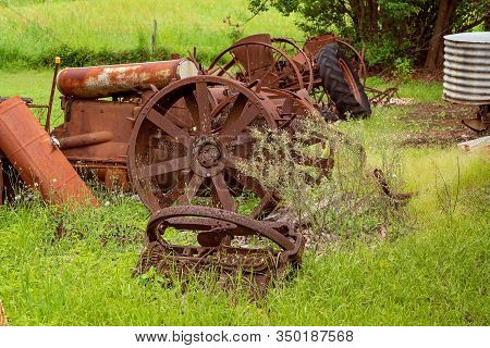 Old Rusted Farm Machinery From A Bygone Era Lying In An Overgrown Field