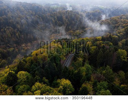 Moody Aerial View Of A Mountain Road Winding Through The Woods In Bavaria, Germany