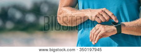 Runner man athlete checking heart rate monitor during workout on wearable tech smartwatch banner panorama.