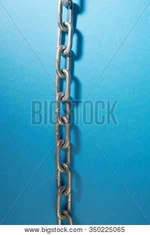 Taunt stainless steel chain on blue background - closeup