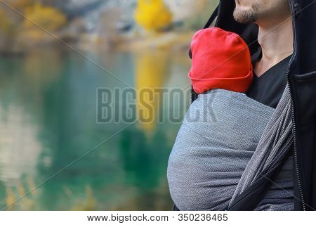 Attractive Young Father With Her Infant Baby In Sling Outdoor. Man Is Carrying Her Child And Travel 