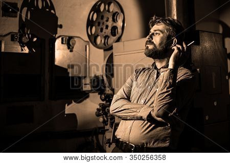 Beautiful Hipster Man Smoking Near A Film Projector In The Room Projectionist